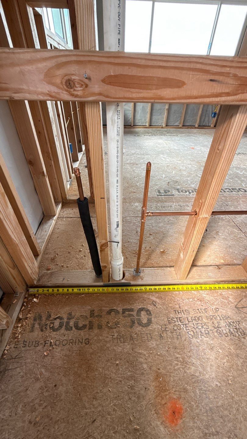 Wooden framing in a construction area with a yellow measuring tape on the floor and concrete surface below.