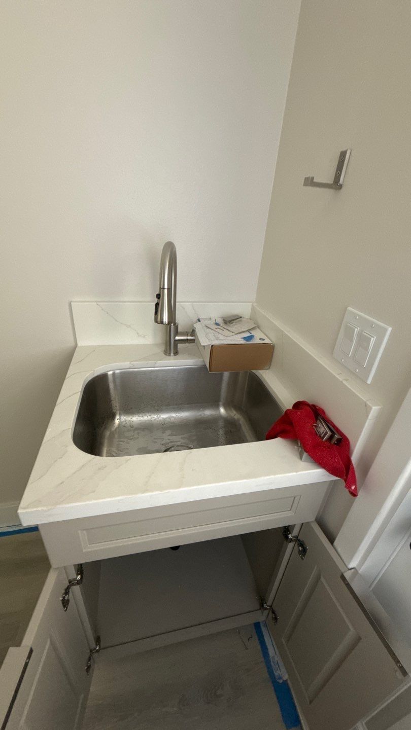 Small utility sink with chrome faucet in a compact room, with a red cloth on the right edge.