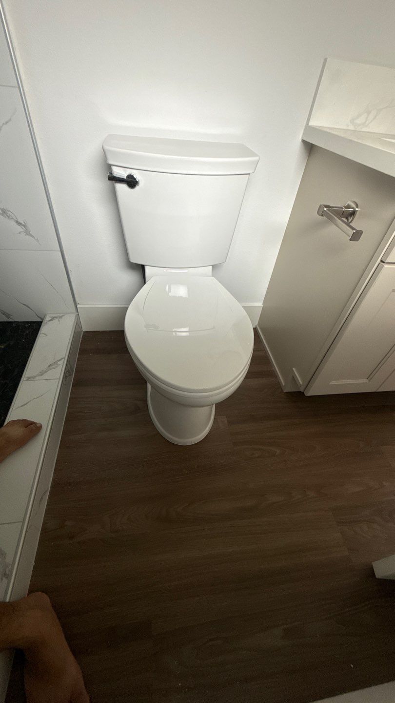 Small bathroom with a white toilet, dark wood floor, and white vanity cabinet.