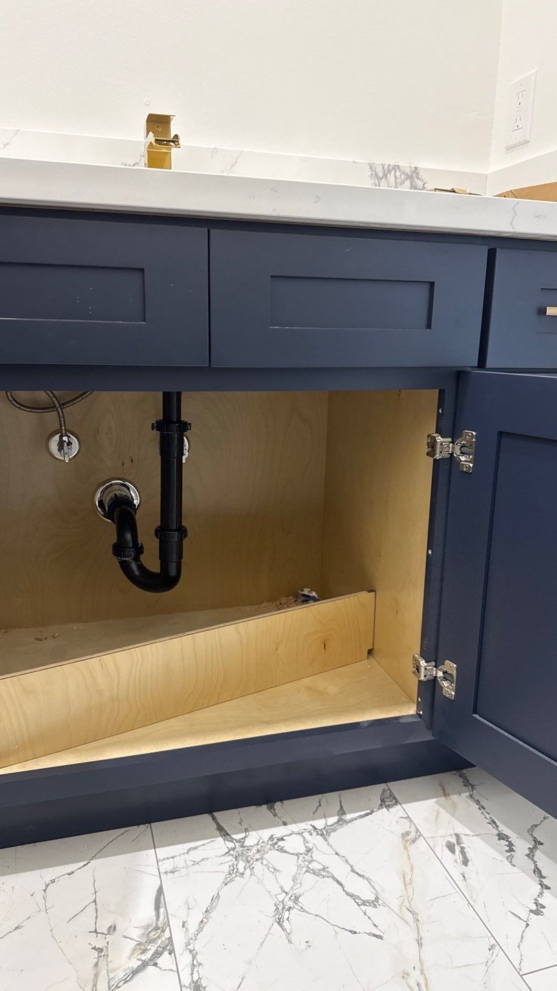 Blue bathroom vanity with open cabinet, exposed plumbing, and white marble-patterned floor tiles