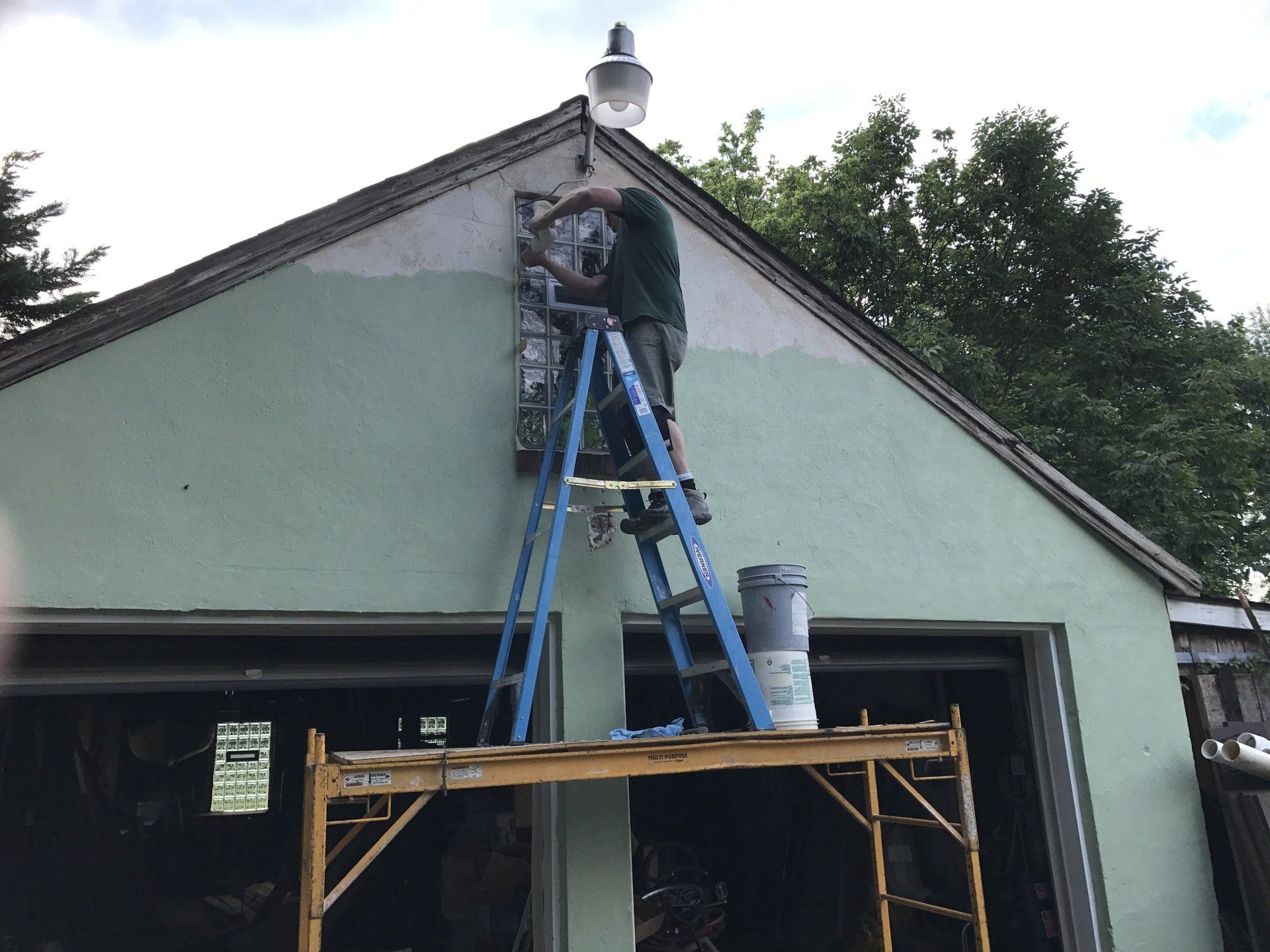 A man on a ladder installing a glass block window