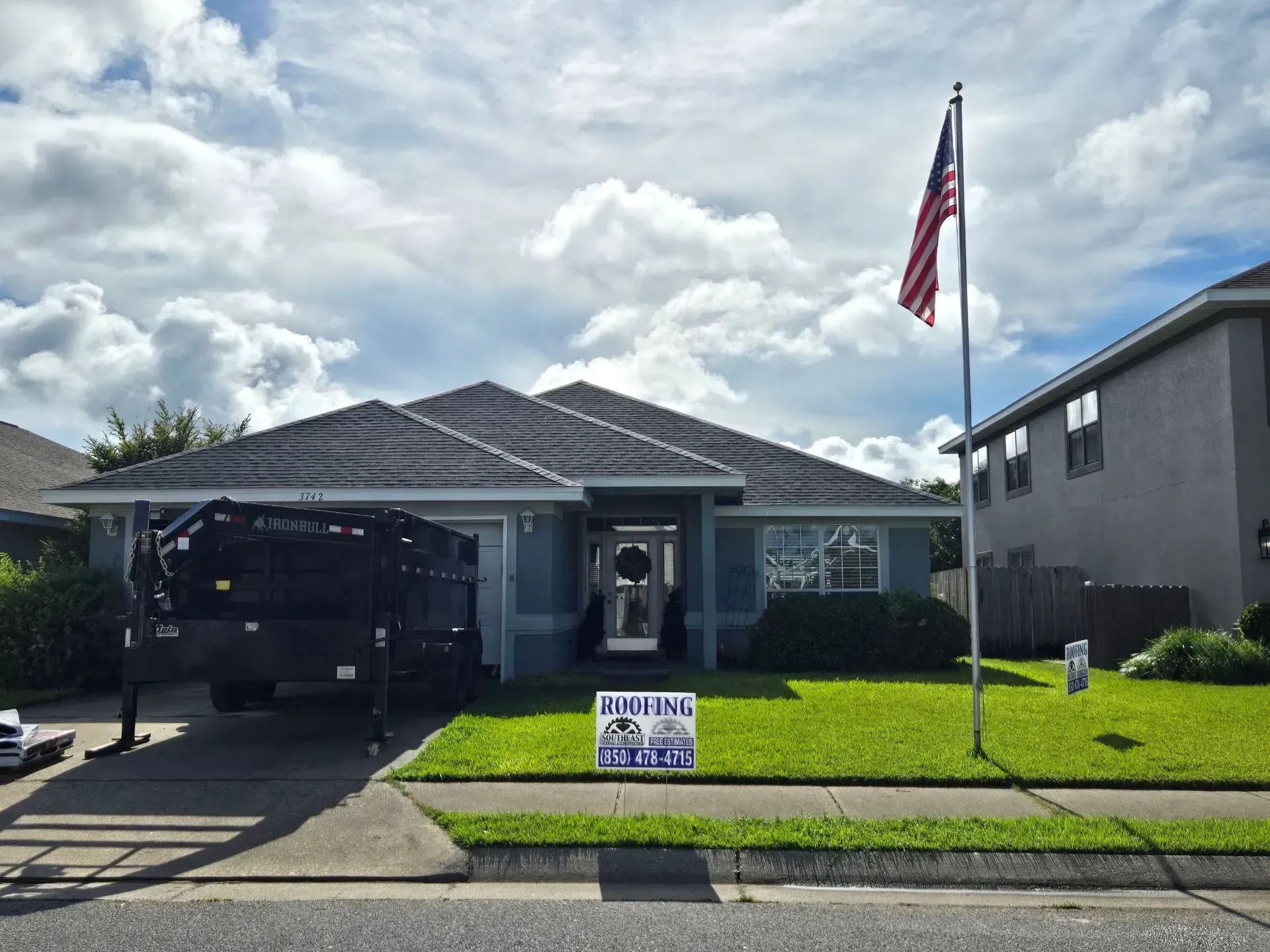 Blue house with American flag, sign on lawn, and truck parked.