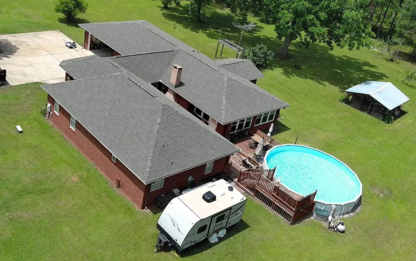 Aerial view of a home with a pool, camper, and green yard.