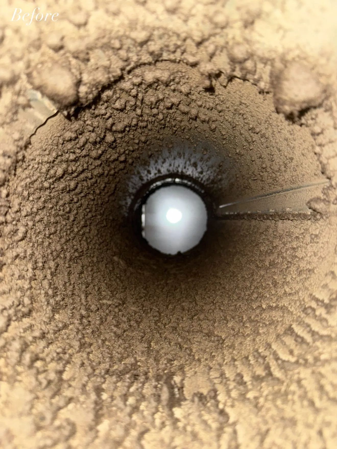 Looking up a chimney, sooty interior with a white ball at the center.