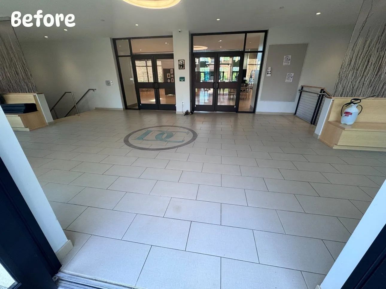 Hallway entrance with glass doors, tiled floor, and small round logo. Text at top left: 