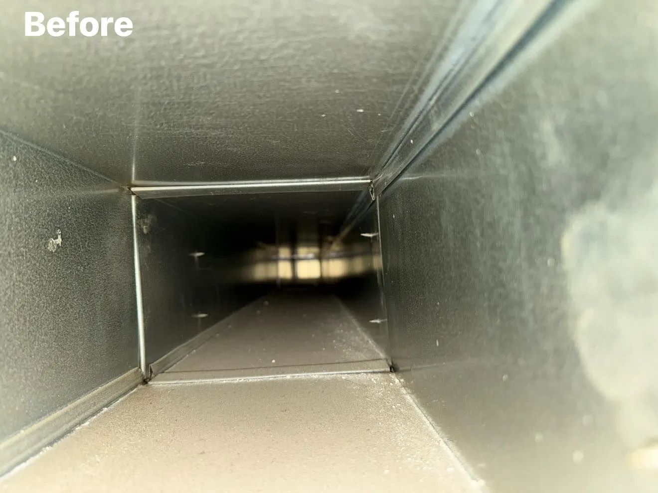 Interior view of a rectangular air duct, coated in dust; 