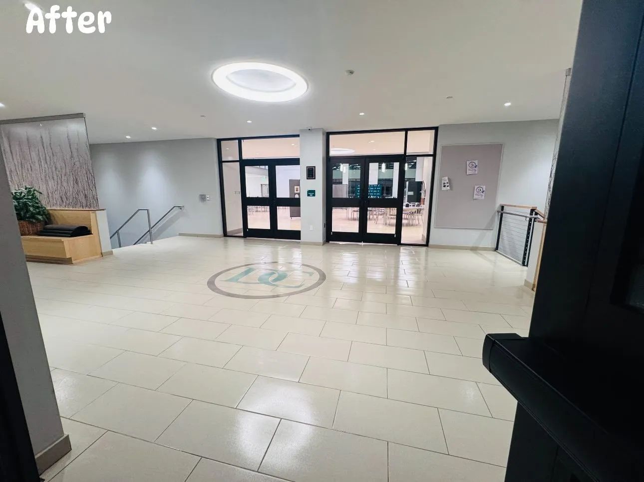 An empty lobby with white tile floor, glass doors, and a round ceiling light.