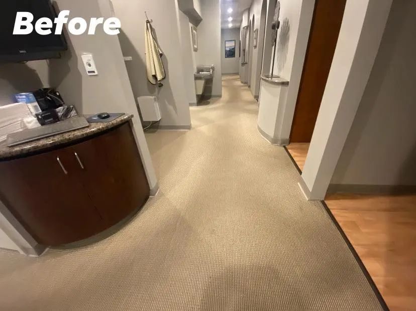 A before photo of a dental office hallway with beige carpet, cabinets, and doorways.