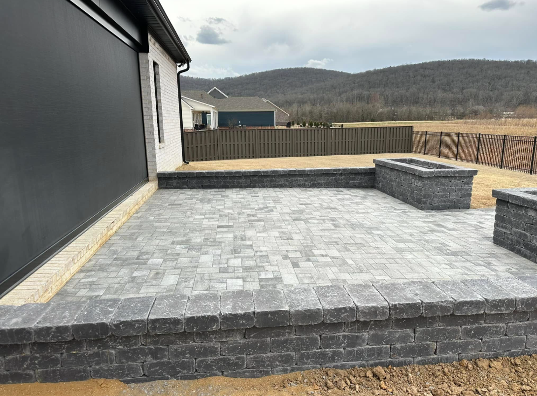 A patio with a fire pit in front of a house with mountains in the background.