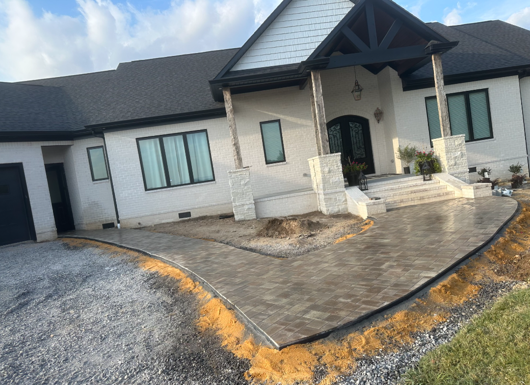 A large white house with a concrete driveway in front of it.