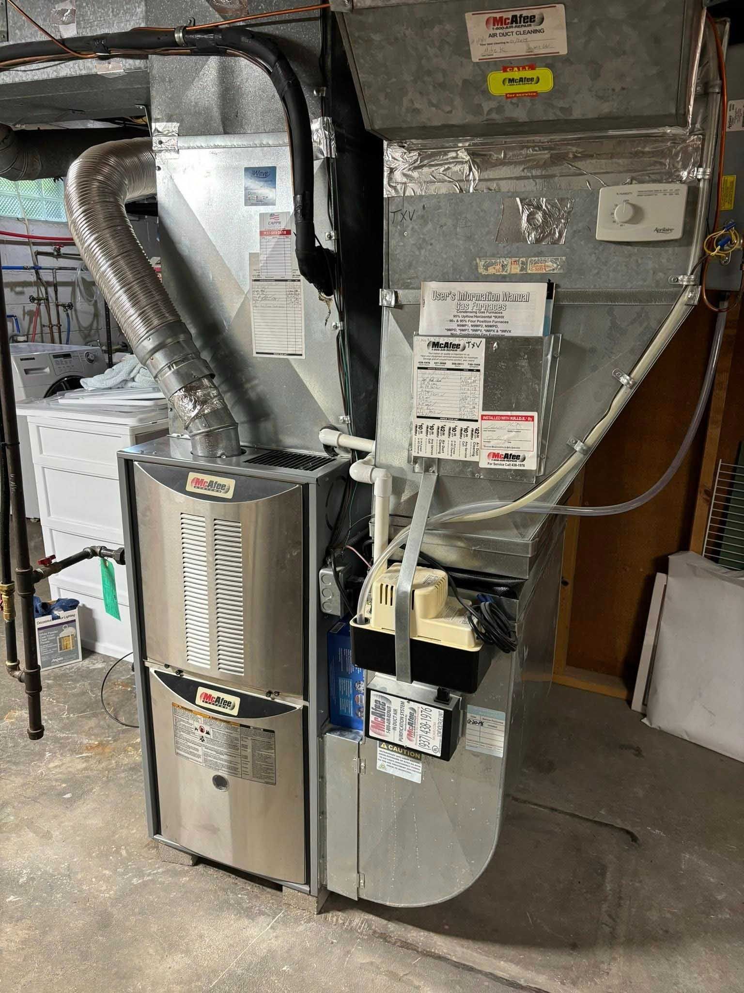 Furnace and air conditioning unit in a basement. Silver metal and white components. Ductwork visible.
