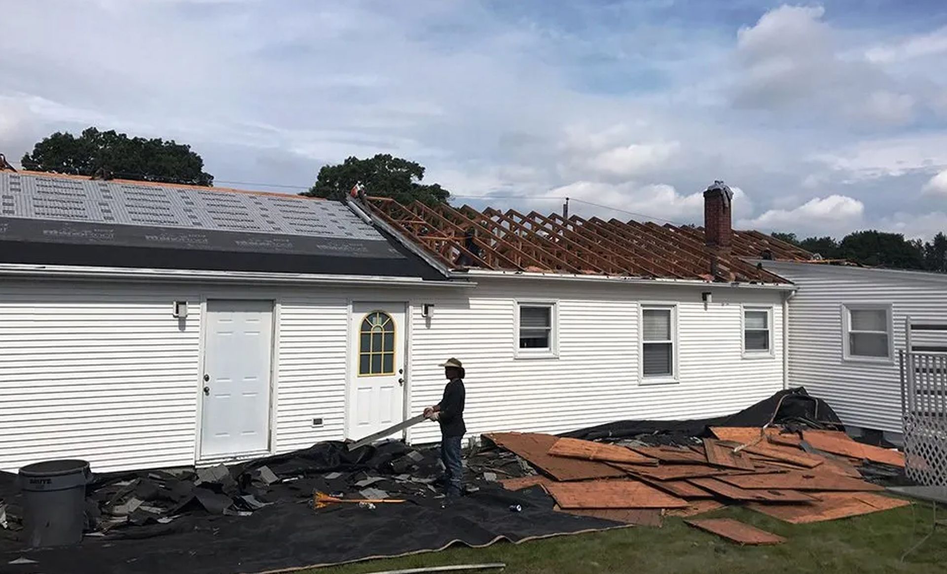 A man is standing in front of a house that has been damaged by a fire.