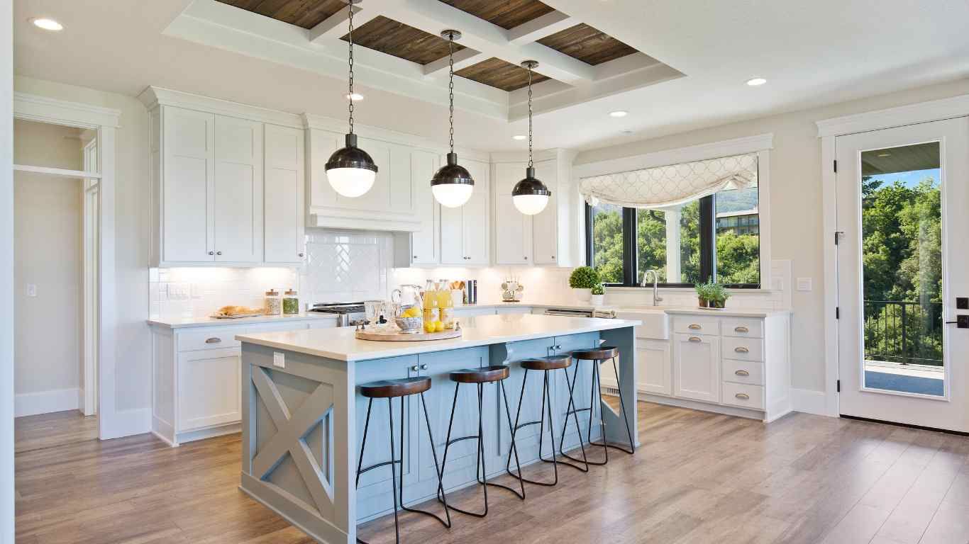 Bright kitchen with light blue island, white cabinets, wood ceiling, and pendant lights.