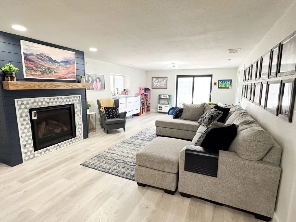 Spacious living room with a gray sectional, fireplace, artwork, and large sliding glass door.