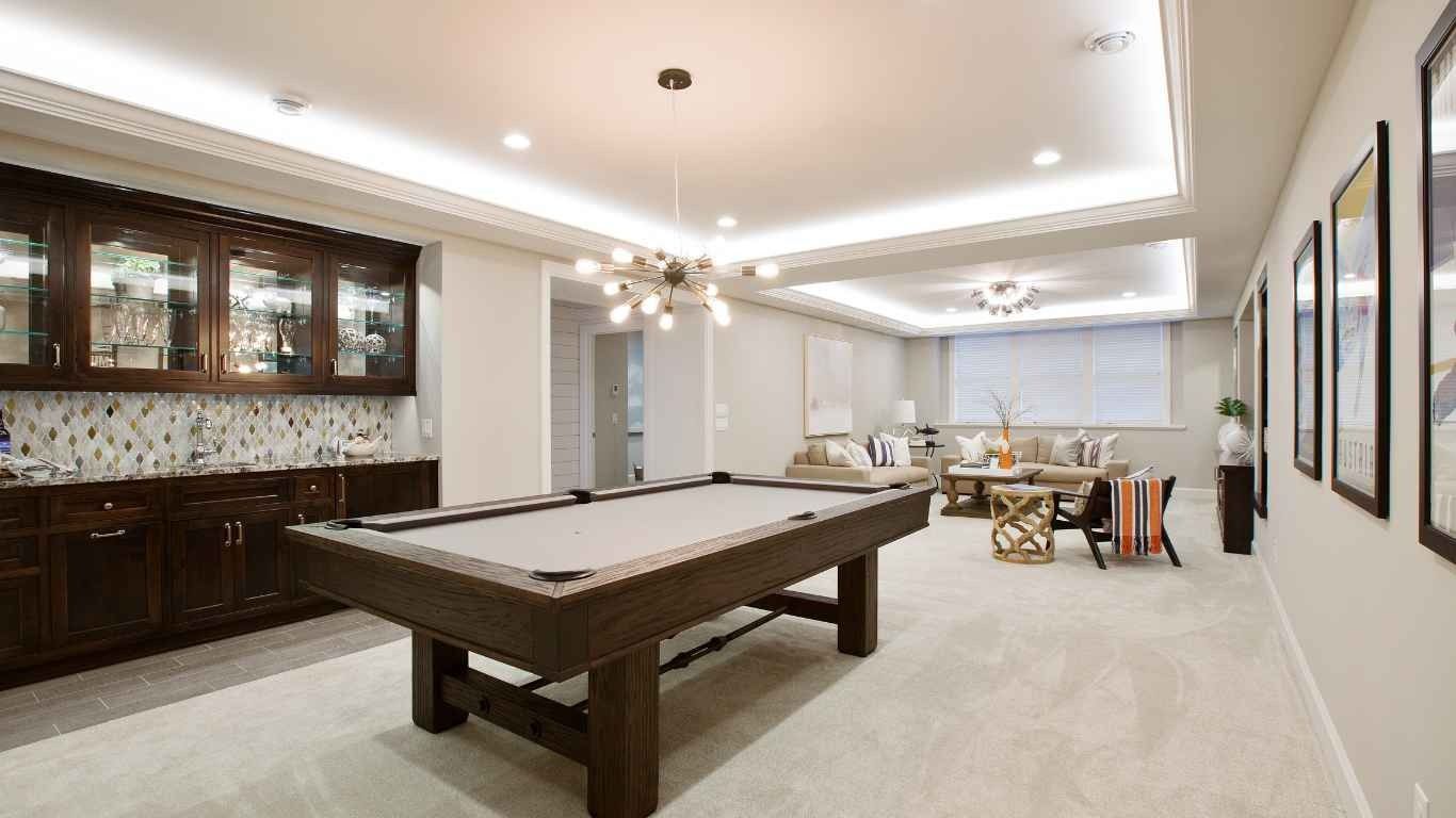 Pool table in a finished basement with a bar, seating area, and artwork.