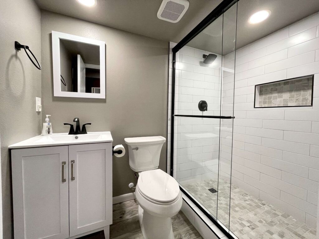 Bathroom with white vanity, toilet, and a tiled shower with glass door.