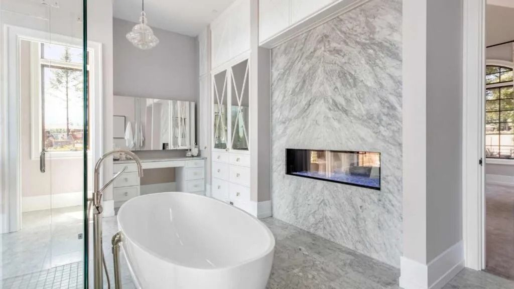 Elegant white bathroom with marble fireplace and freestanding tub.