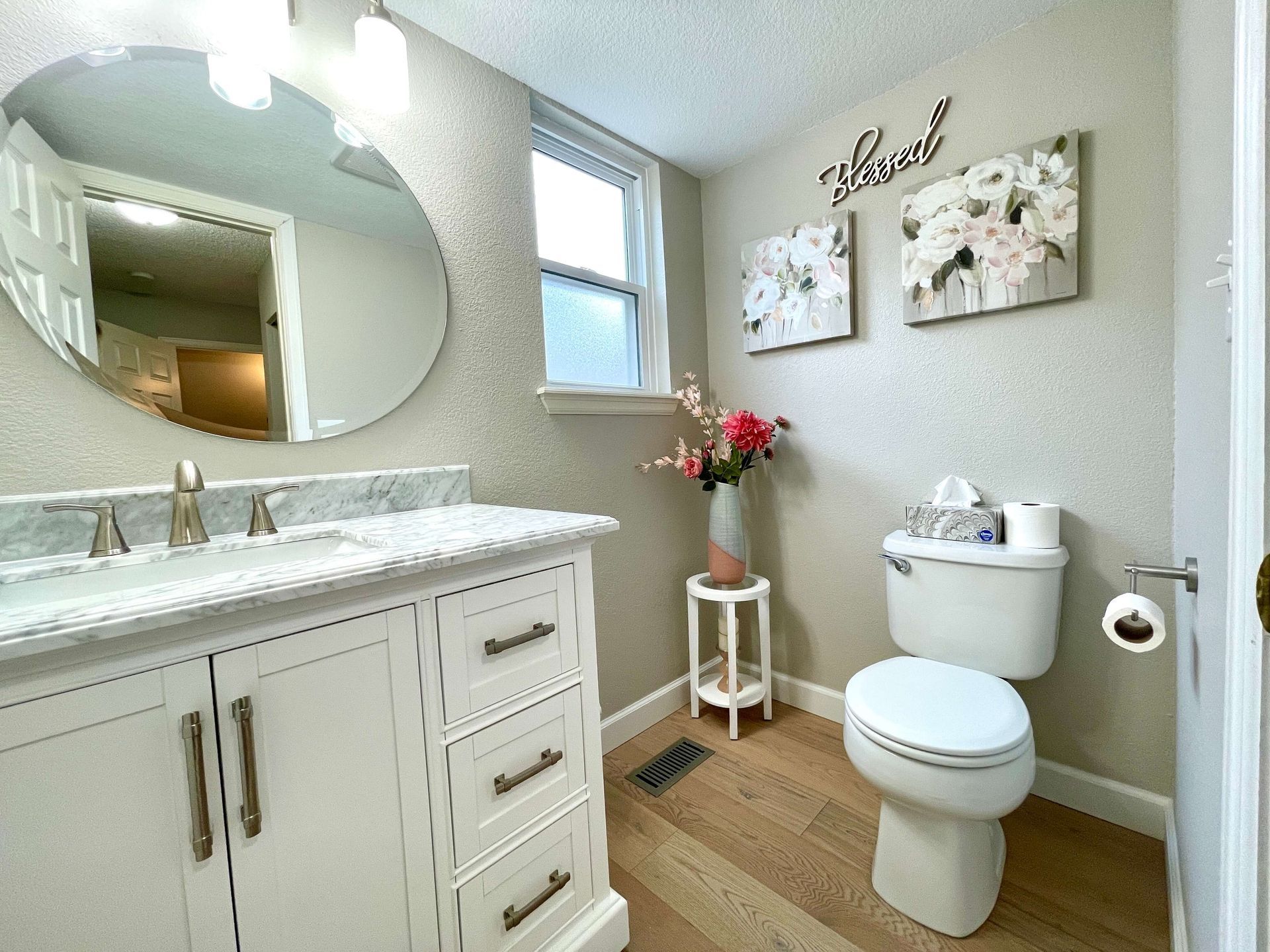 White bathroom with vanity, toilet, and floral decor.