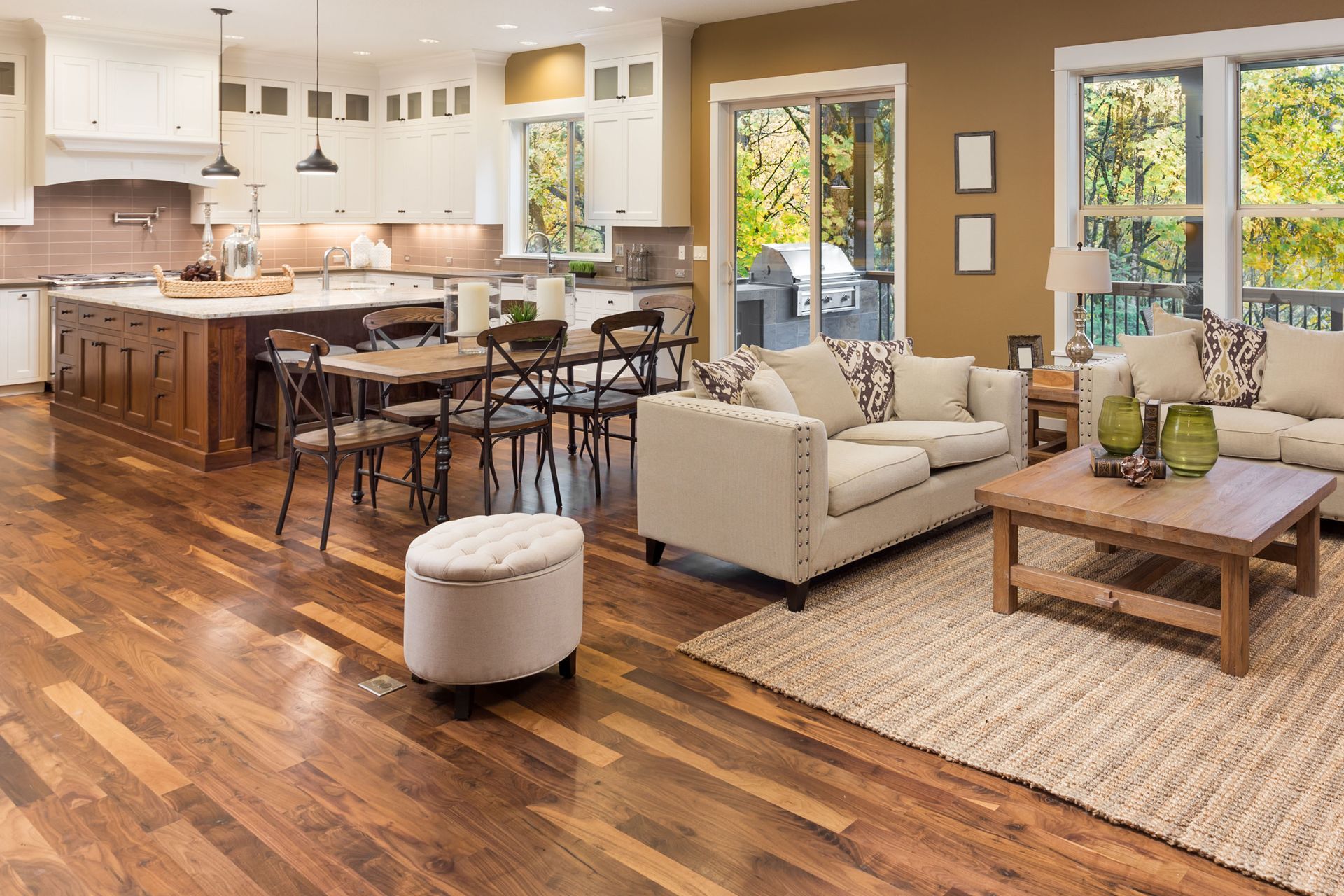Open-concept home featuring a modern white kitchen, wood island, dining area, and a neutral-toned living room.