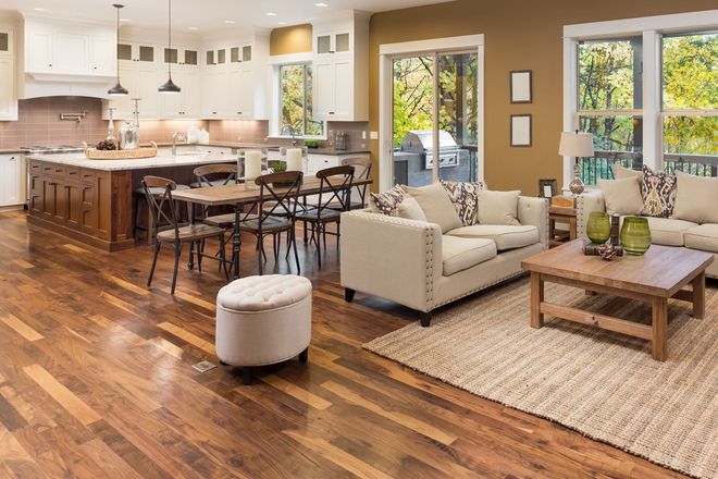 Open-concept home featuring a modern white kitchen, wood island, dining area, and a neutral-toned living room.