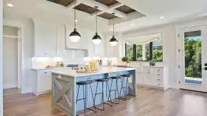 Kitchen with island, light blue cabinetry, pendant lights, and wooden floors.