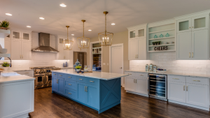 Spacious kitchen with blue island, white cabinets, stainless steel appliances, and wood floors.