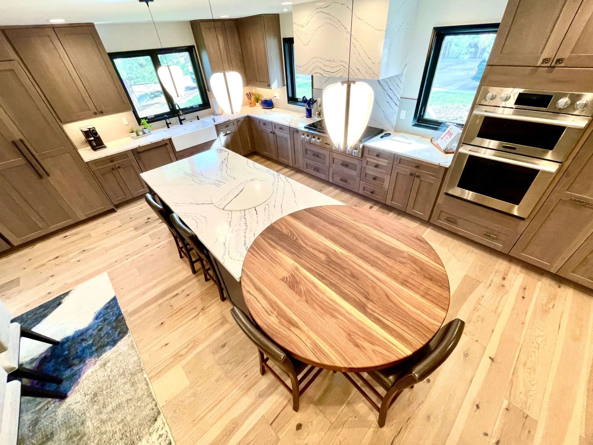 Modern kitchen with a large island and a wooden table. Light wood cabinets and floor.