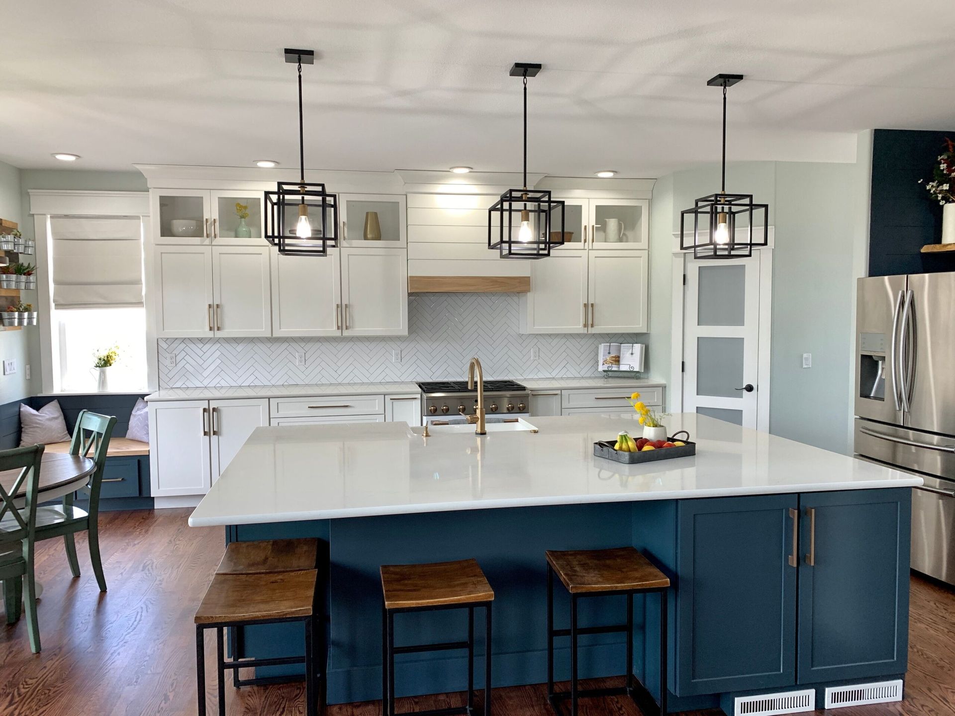 Modern kitchen with blue island, white cabinets, and black pendant lights.