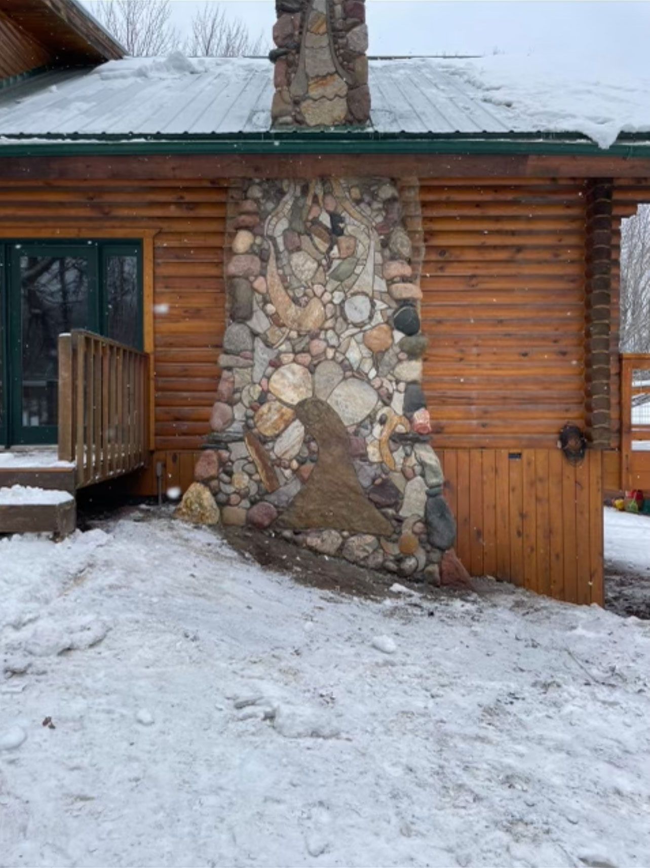 A log cabin with a stone fireplace in the snow