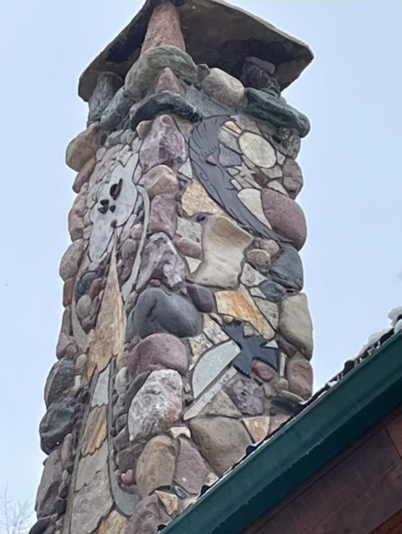 A chimney made of rocks on top of a building designed with moon and old man figure