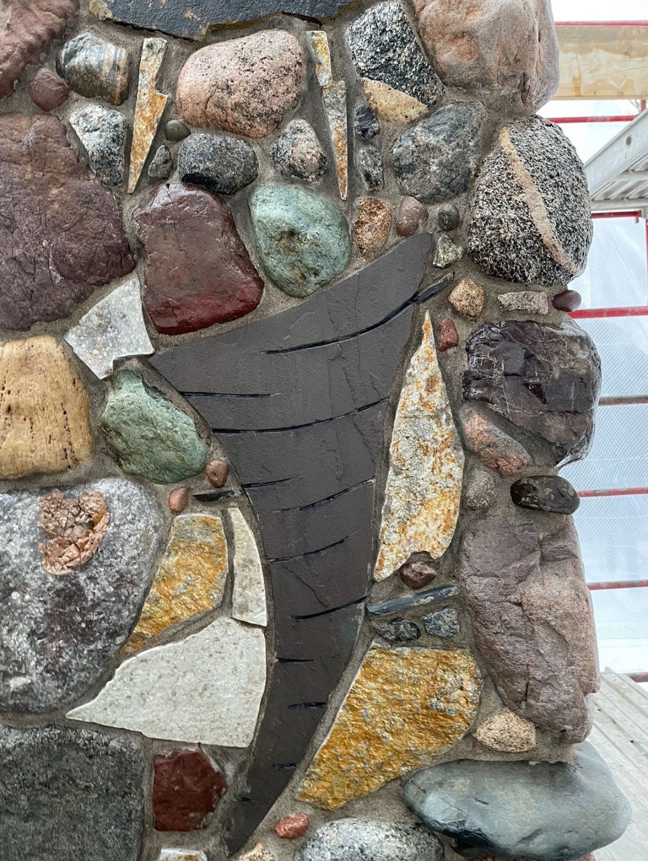 A close up of a stone wall with a winter twister sculpture in the middle