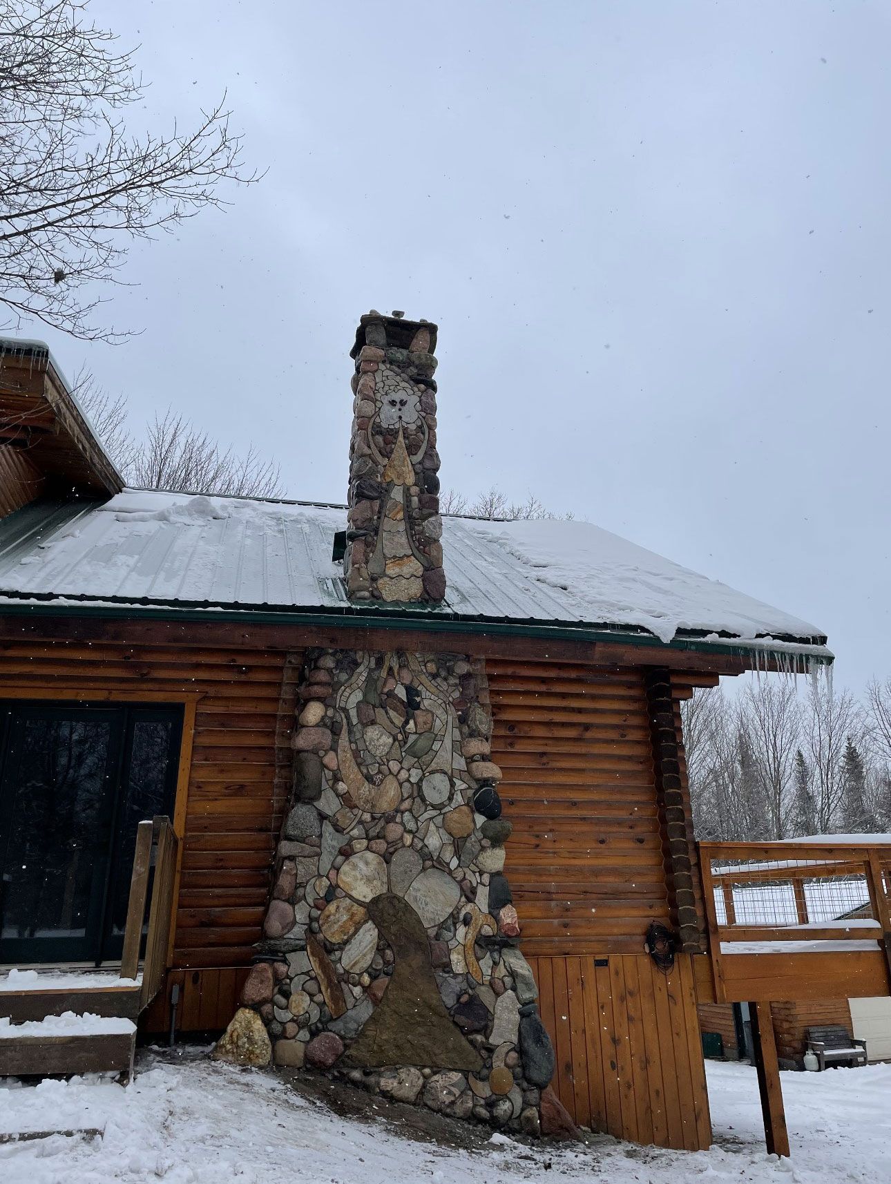 A log cabin with a stone chimney on the side of it