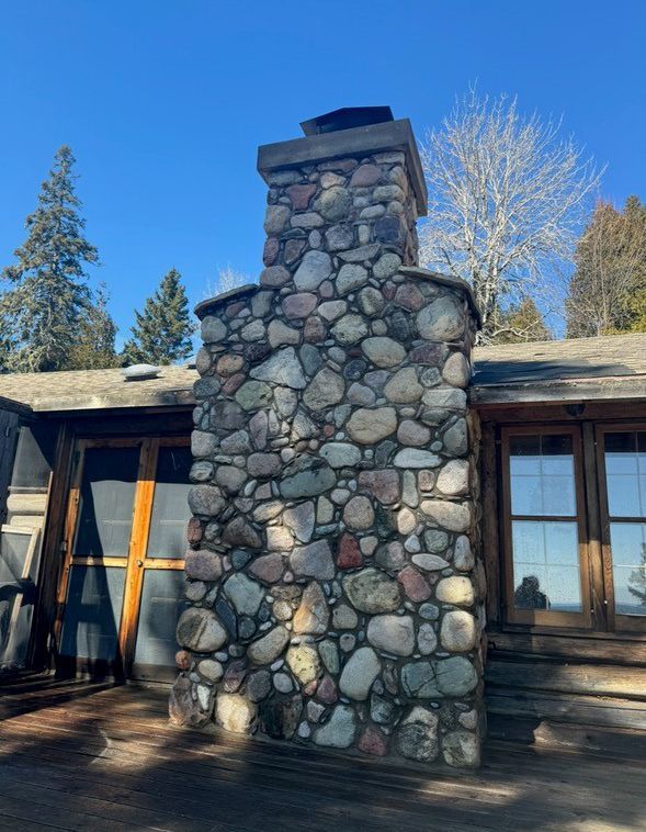 A large stone chimney is on the side of a house.