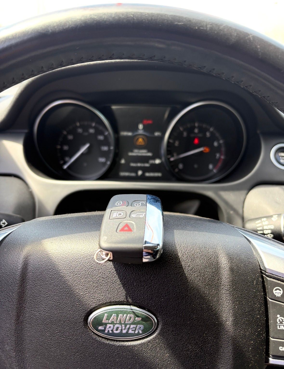 Land Rover steering wheel and dashboard with a key fob resting on top.