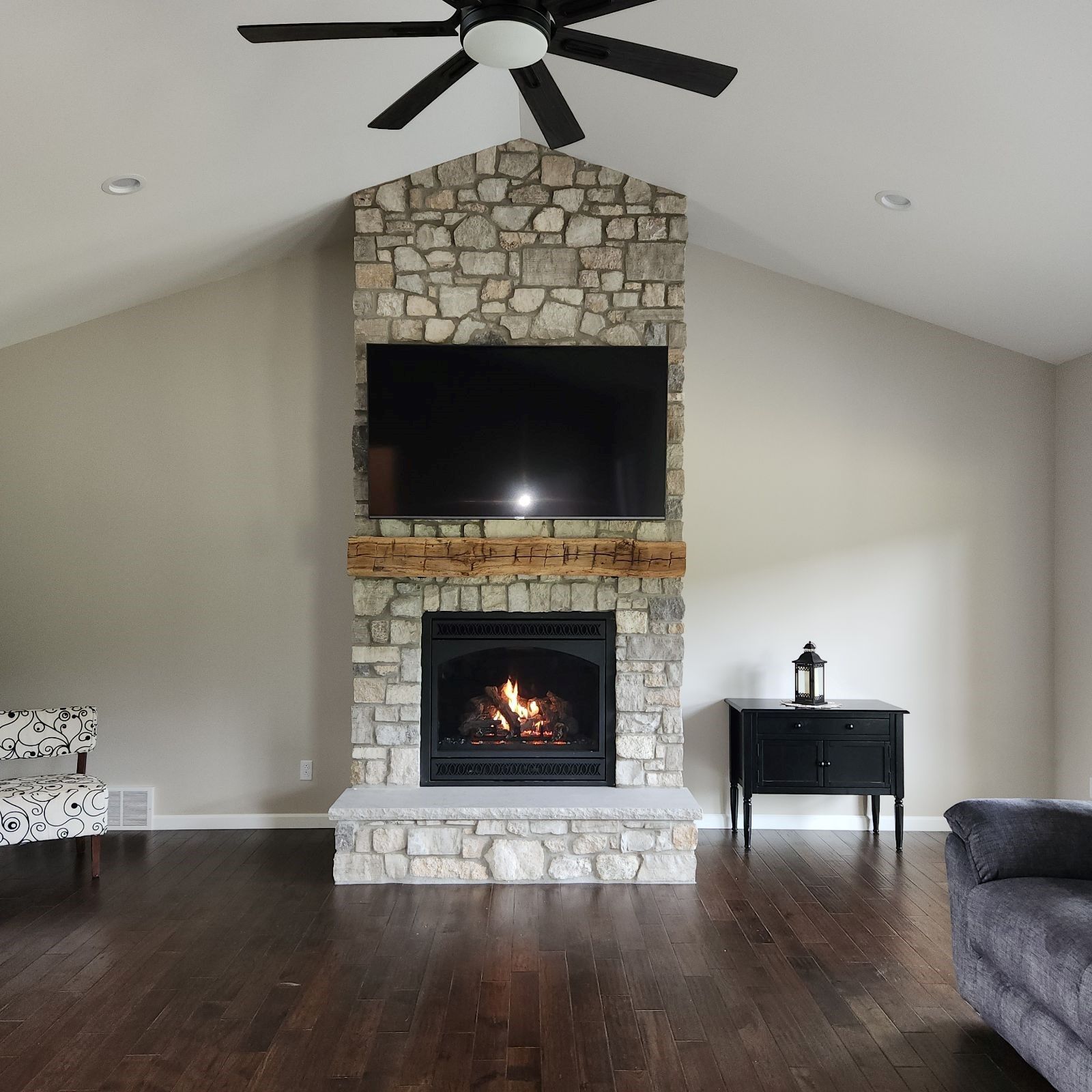 A living room with a stone fireplace and a flat screen tv