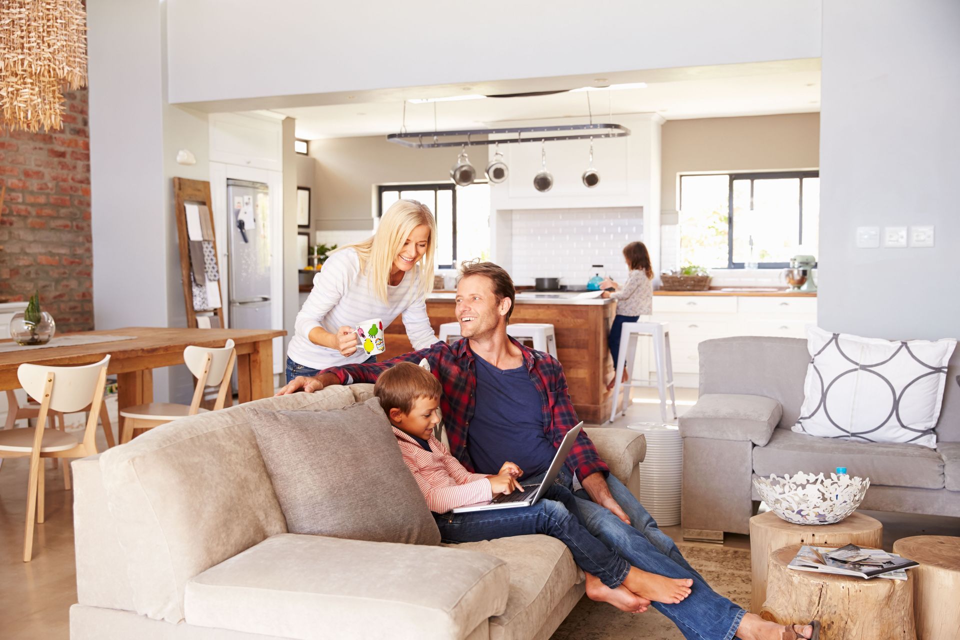 A family is sitting on a couch in a living room looking at a laptop.