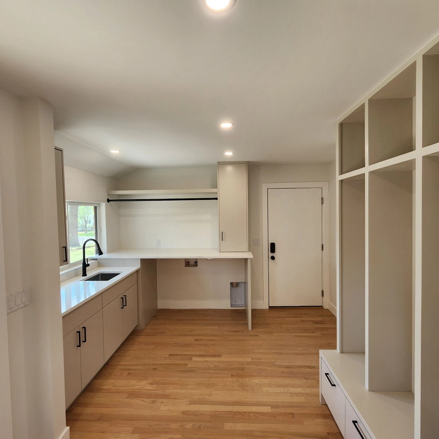 A kitchen with hardwood floors and white cabinets