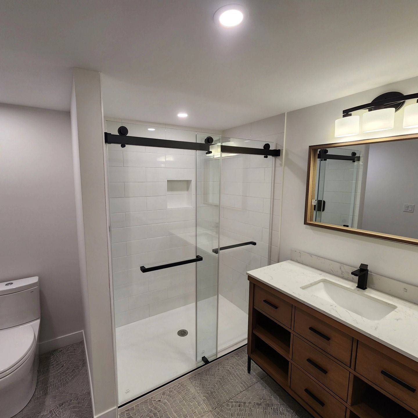 A bathroom with a toilet , sink , shower and mirror.