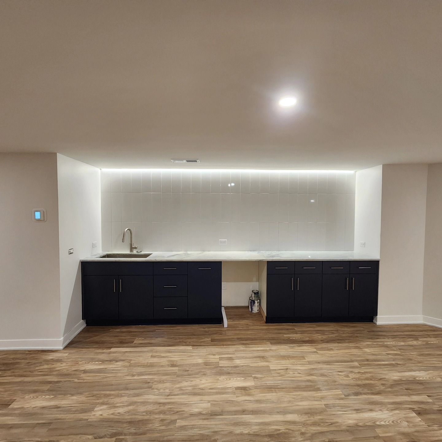 A kitchen with black cabinets and a sink in a basement.