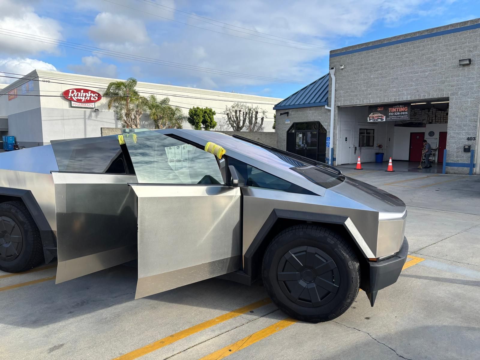 Tesla Cybertruck with open doors at a car wash, outdoors.