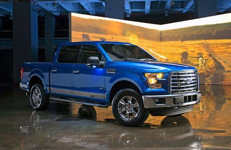 Blue Ford F-150 pickup truck parked indoors, metallic finish, with a landscape backdrop.