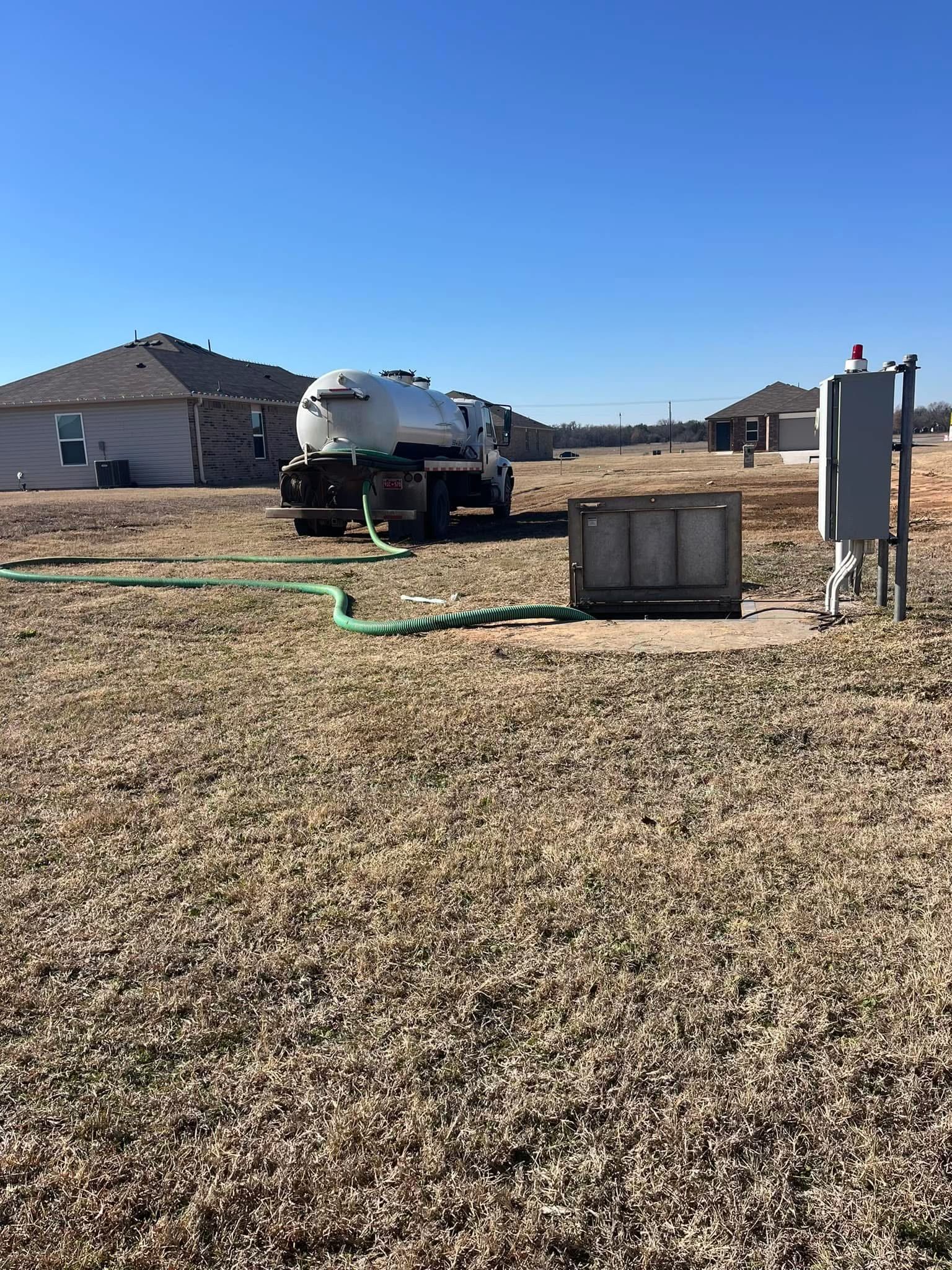 Septic tank riser with grime, electrical cord, and float; green lid in grass.