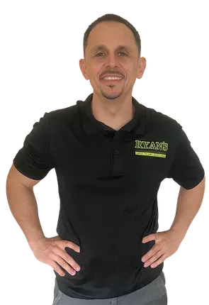 A smiling person wearing a black polo shirt with a logo on the chest, standing with hands on hips against a white background.