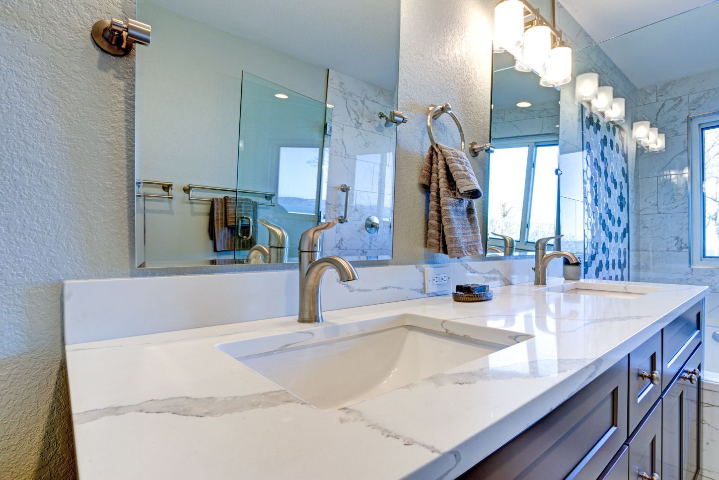 Modern bathroom vanity with a white marble countertop, double sinks, dark wooden cabinets, and a large mirror.