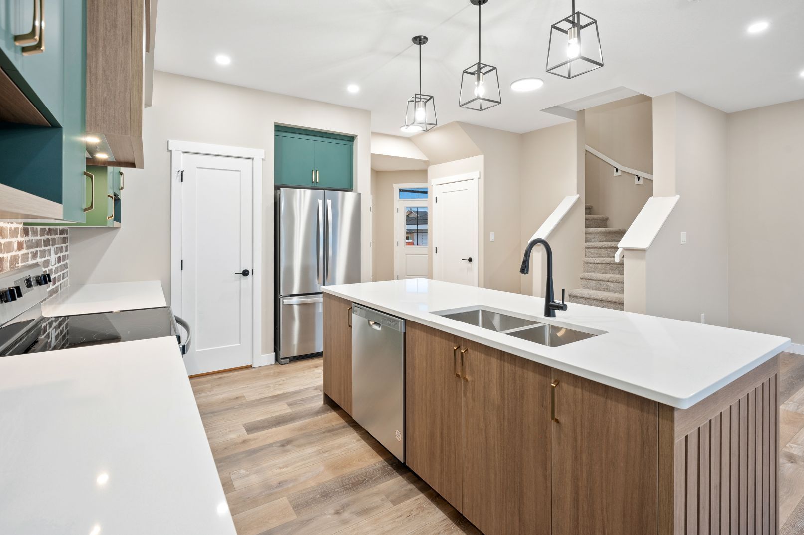 Modern kitchen featuring wood-tone island cabinetry, white quartz countertops, stainless appliances, and pendant lighting.
