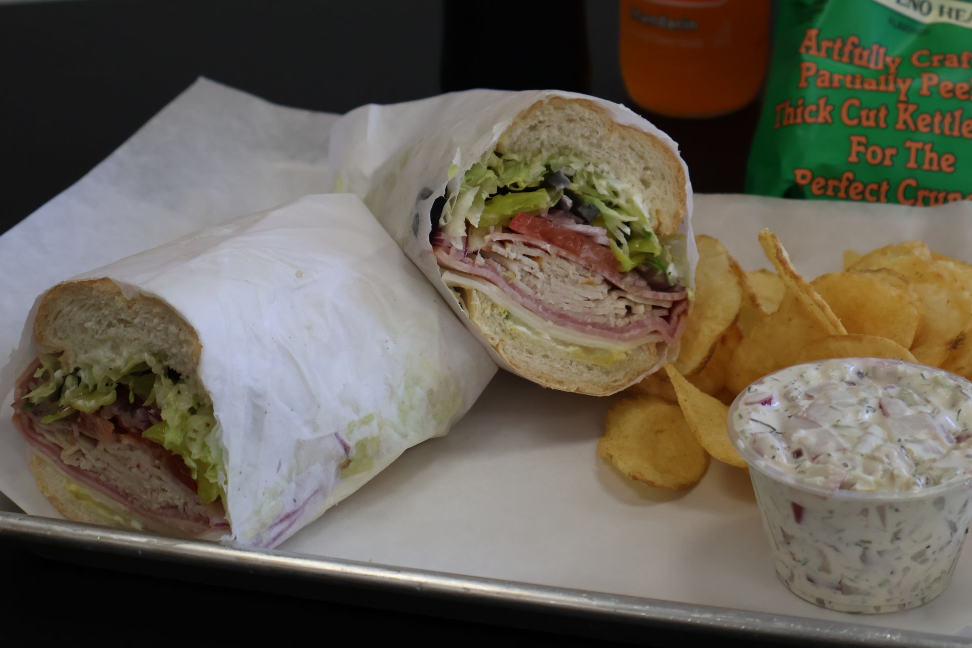 Wrap sandwich with chips and a dipping cup on a tray.