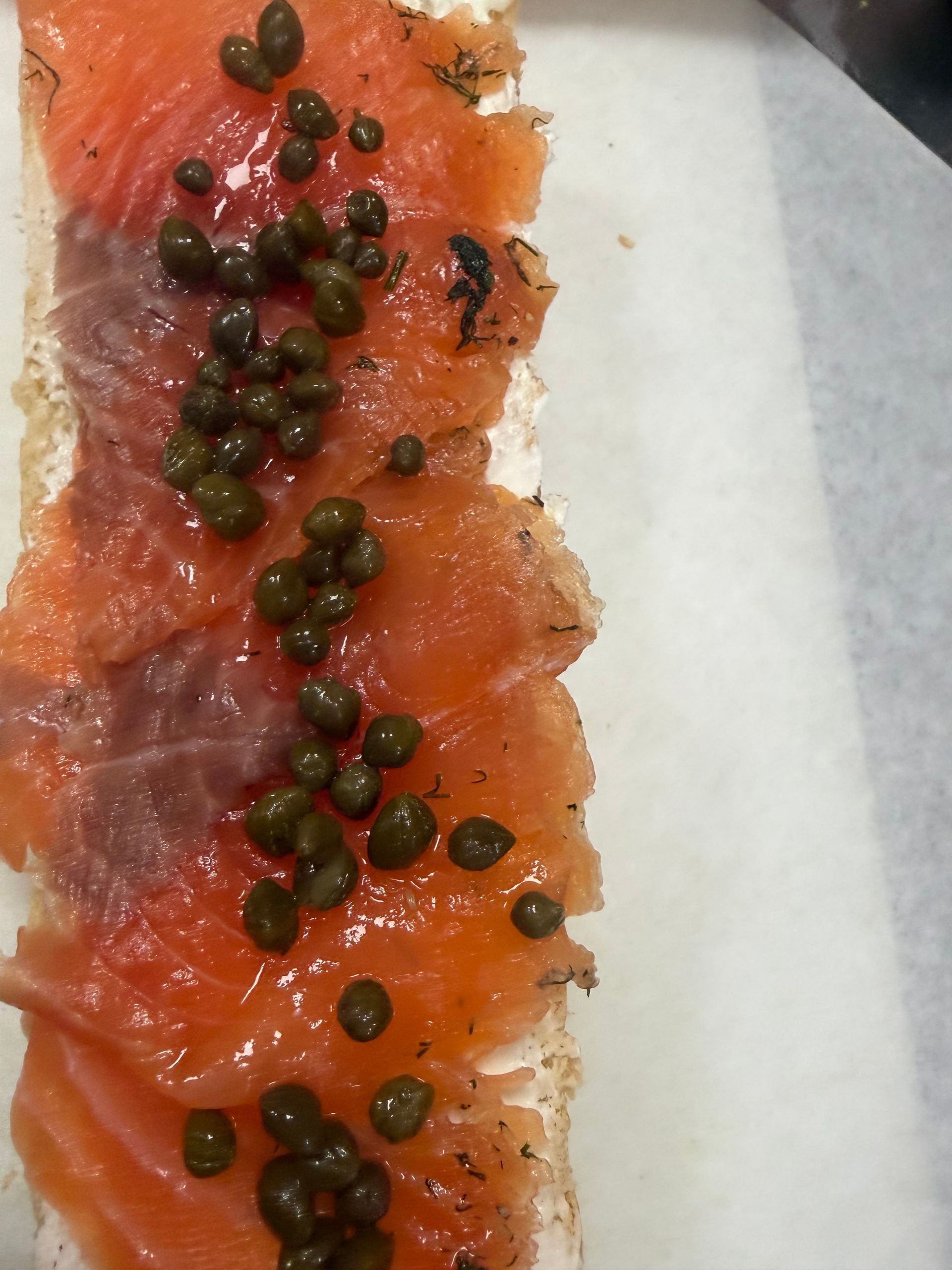 Close-up of raw salmon topped with black caviar on parchment paper.