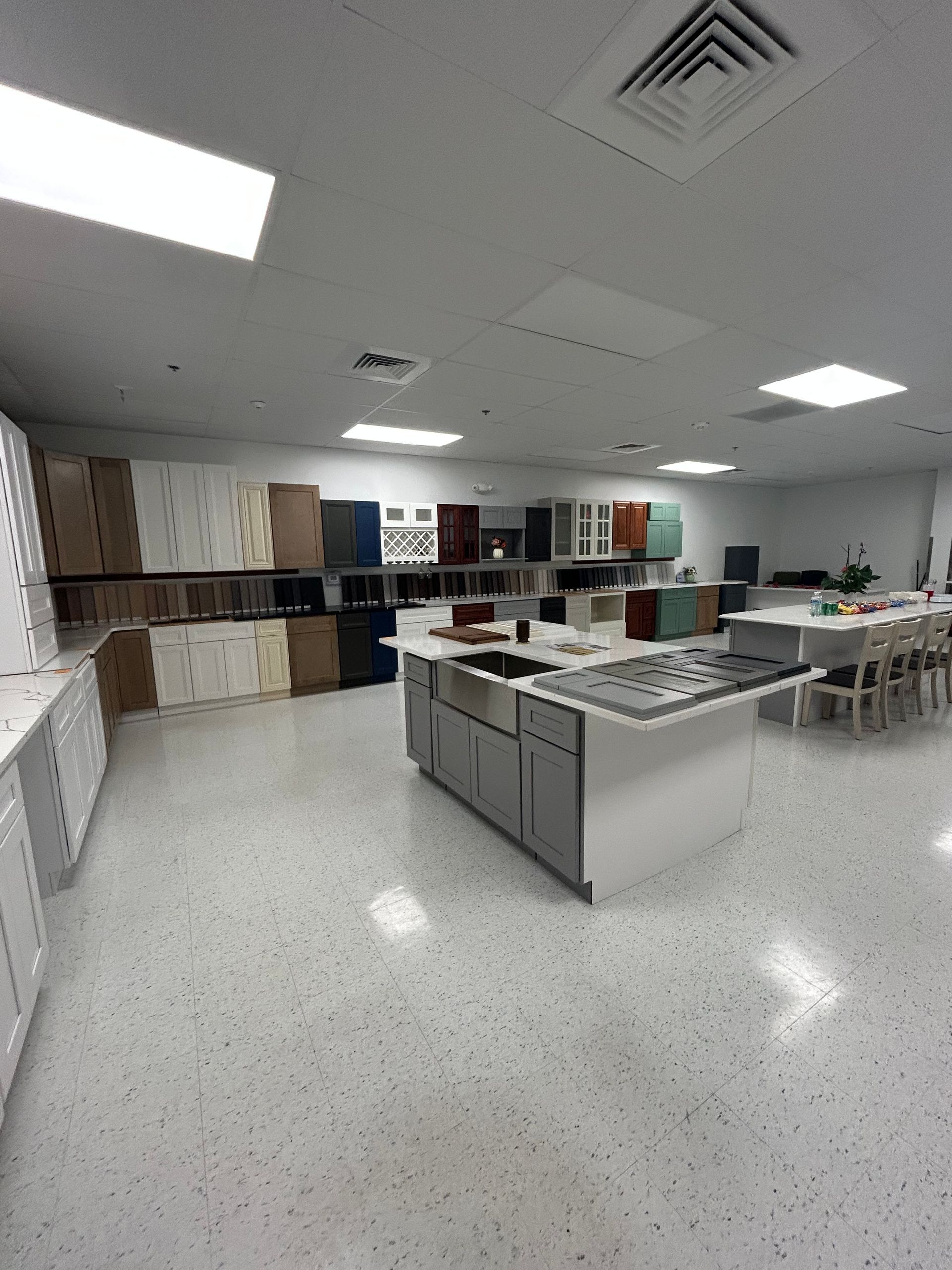Kitchen cabinet showroom featuring various cabinet styles and a central island.