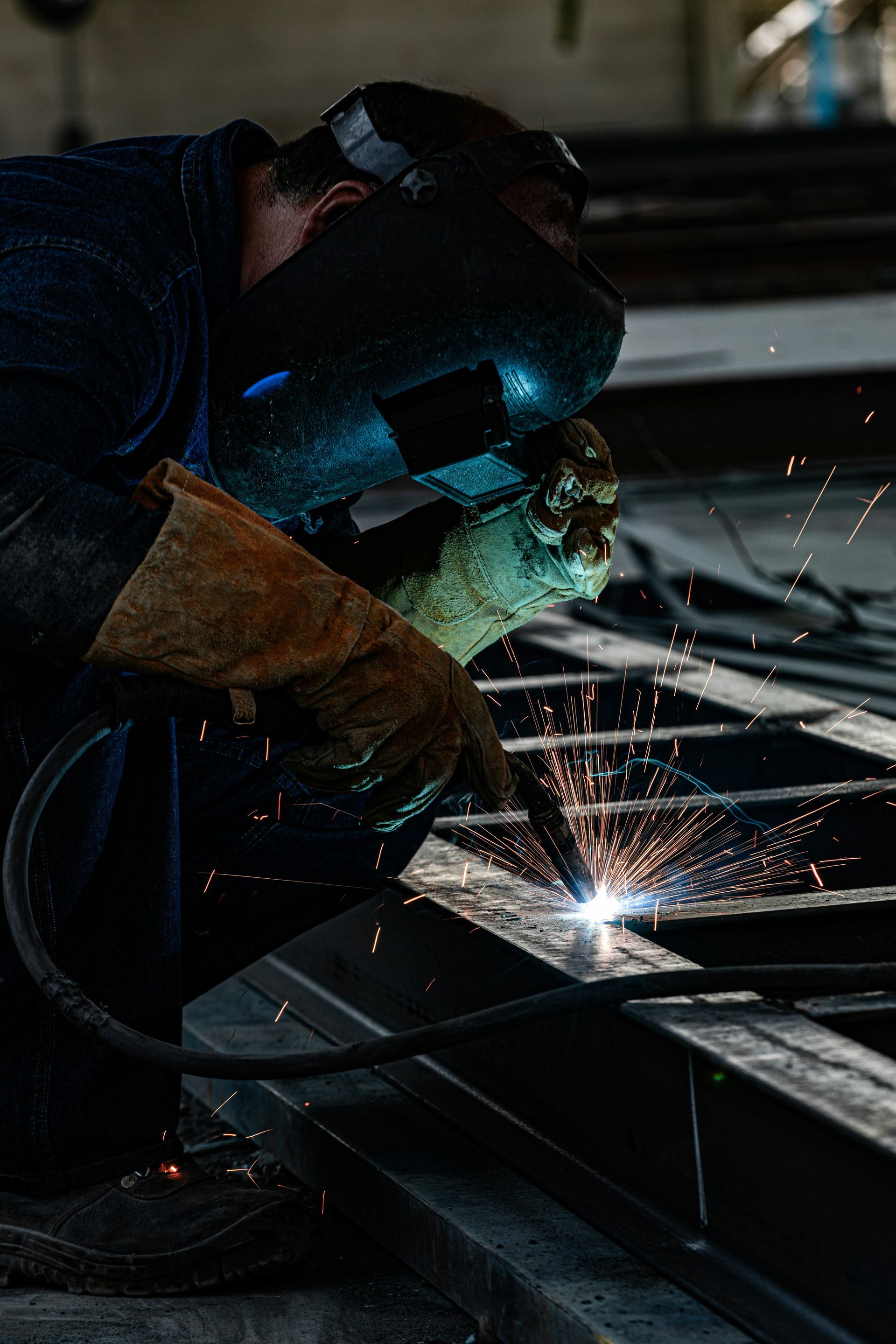 A man is welding a piece of metal in a factory.
