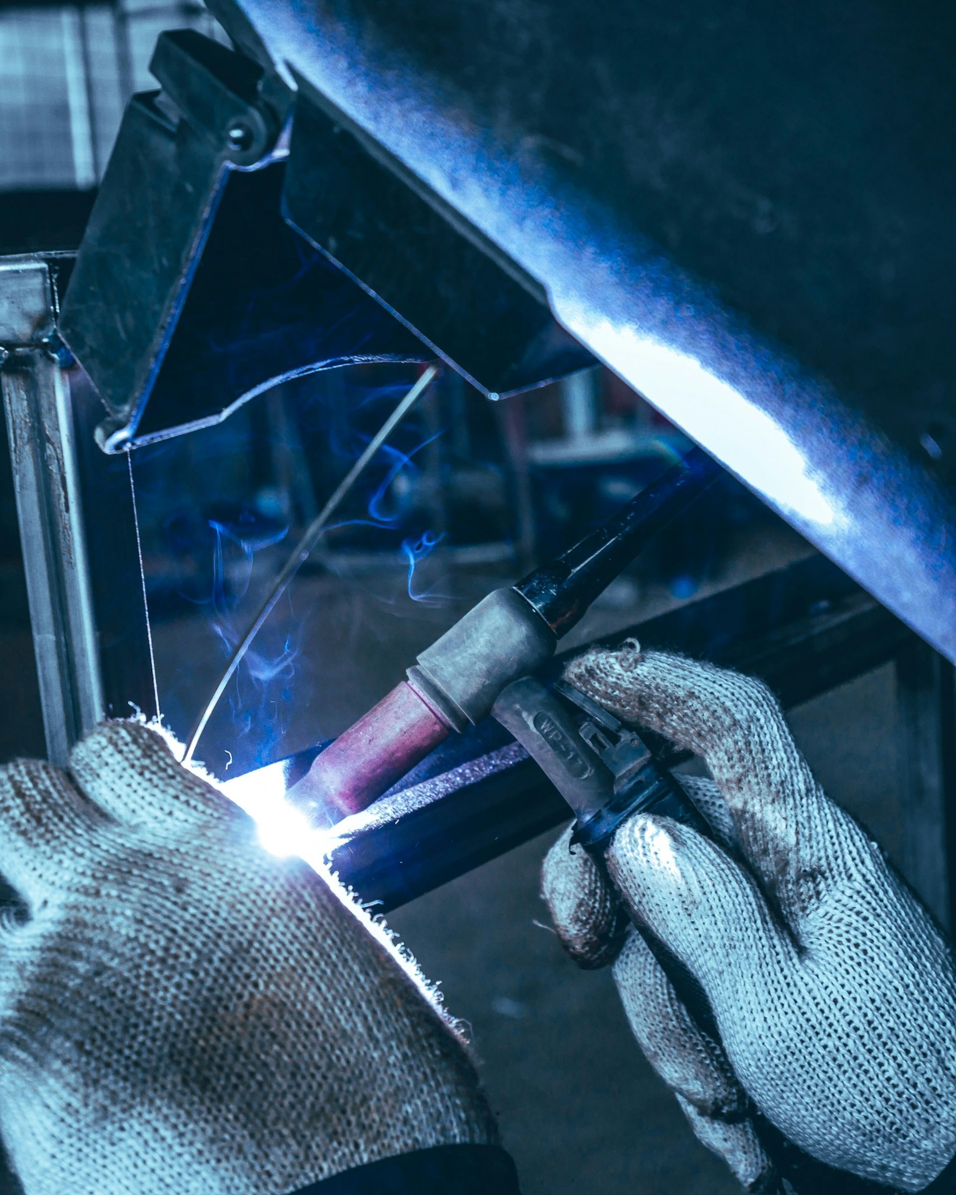 A person is welding a piece of metal in a factory.